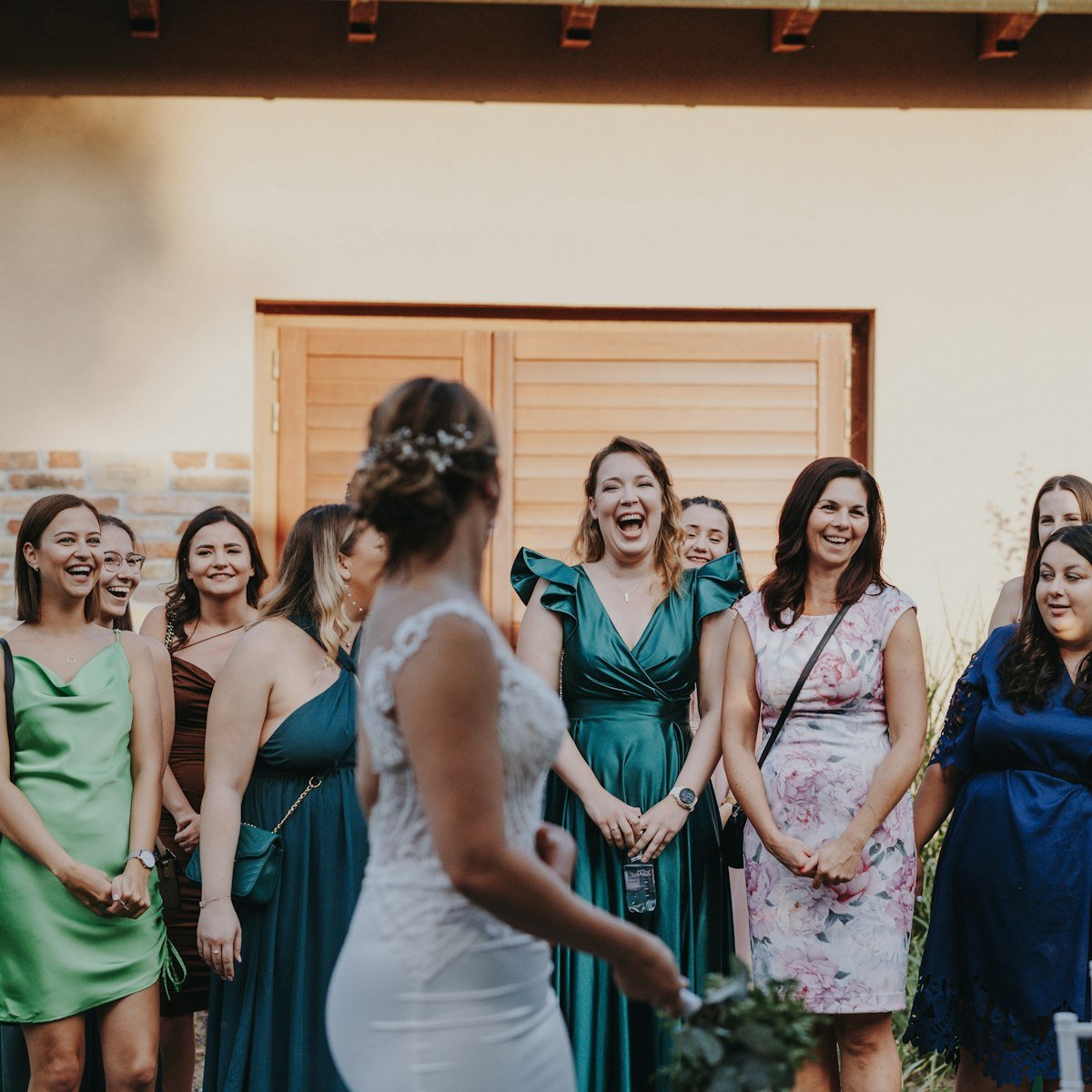 A group of bridesmaids in coordinated aso ebi dresses laughing together.