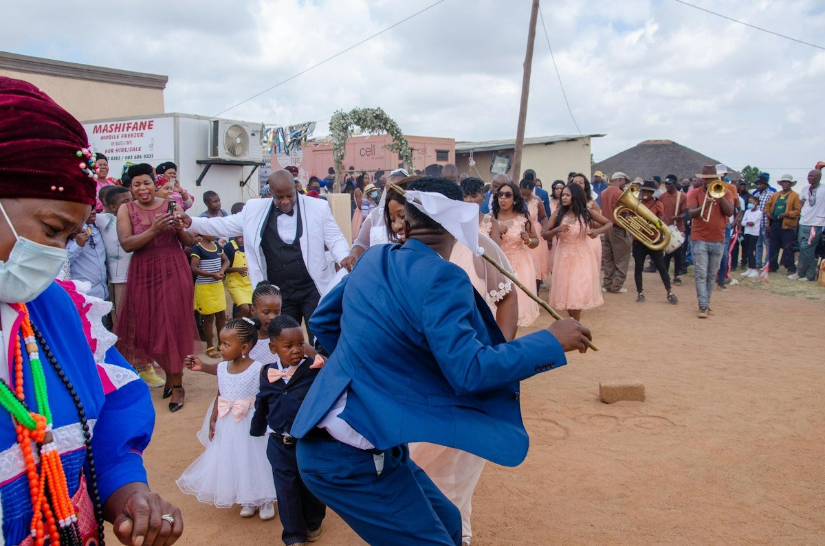 A lively dance scene with guests celebrating in coordinated asoebi styles.