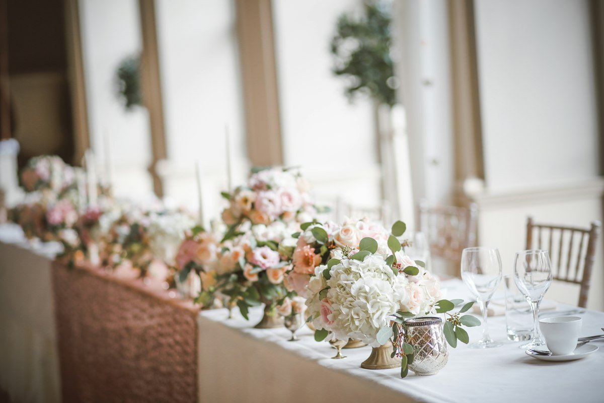 An elegant wedding table setting adorned with vibrant floral arrangements and gold accents.